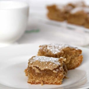 Two pieces of easy peanut butter cake on a white plate with the whole cake in the background.