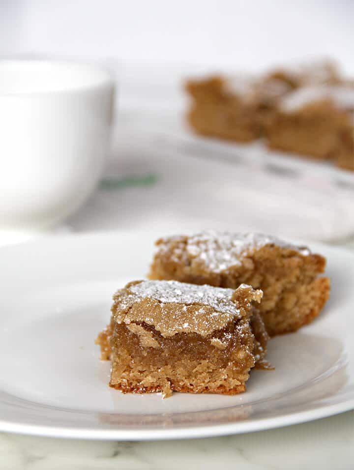 Two pieces of easy peanut butter cake on a white plate with the whole cake in the background.