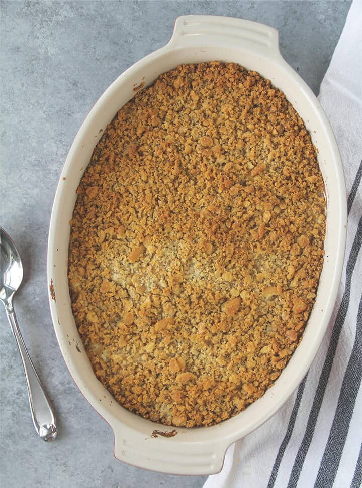 Baked poppy seed chicken casserole in a dish with a striped towel.