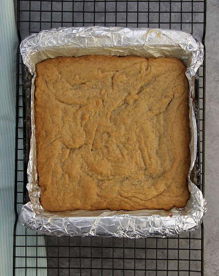 Easy peanut butter cake in a square dish on a cooling rack.