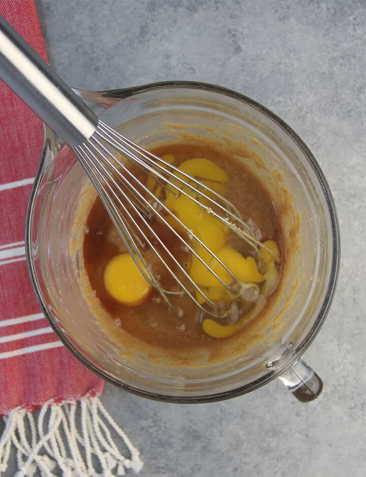 Eggs, butter, and peanut butter in a bowl with a whisk.