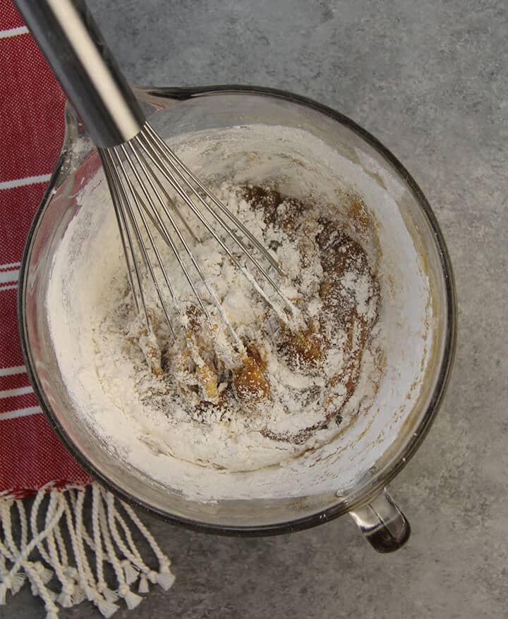 A bowl of cake batter stirred with a whisk.