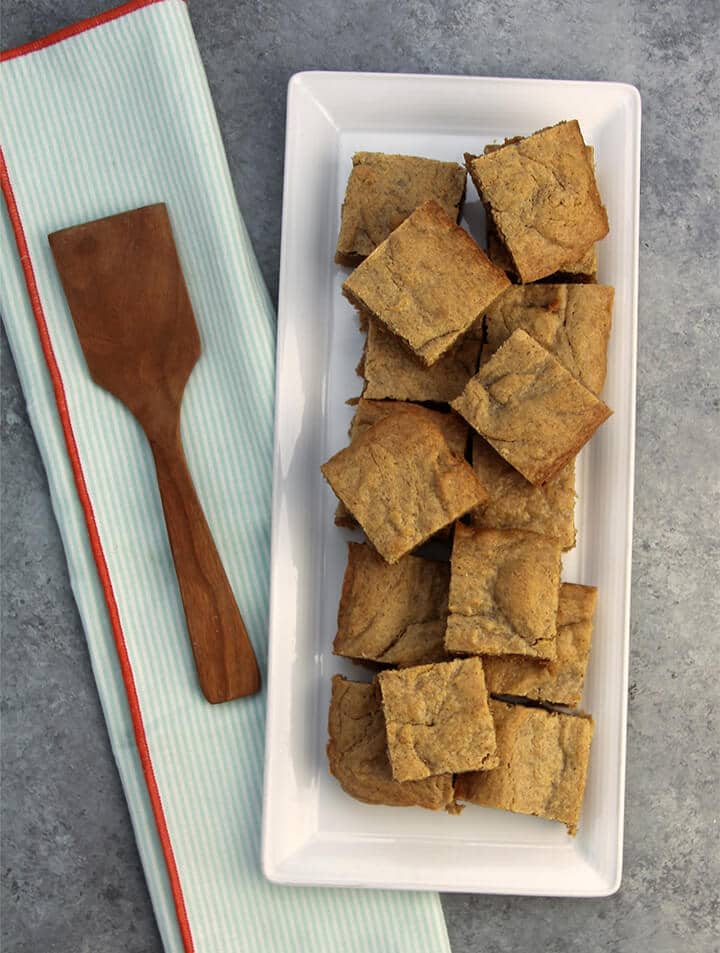 Easy Peanut Butter Cake cut into squares and on a white platter.