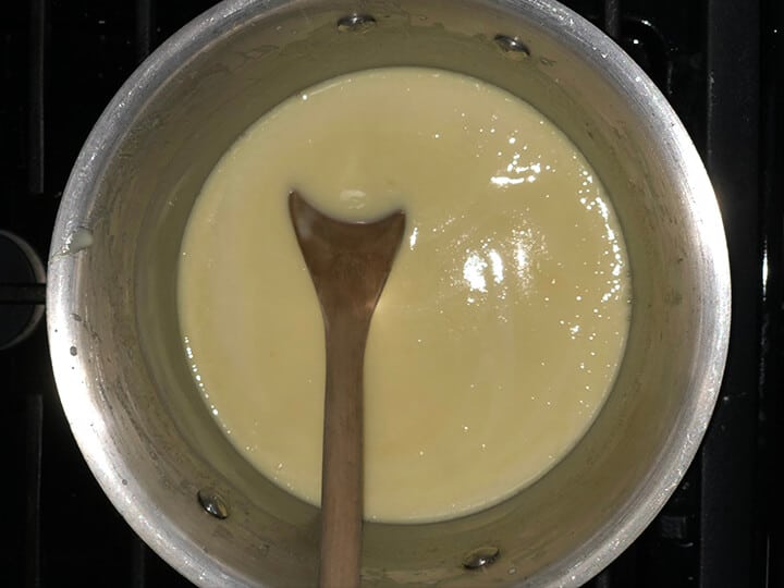 Saucepan with lemon filling and a wooden spoon.