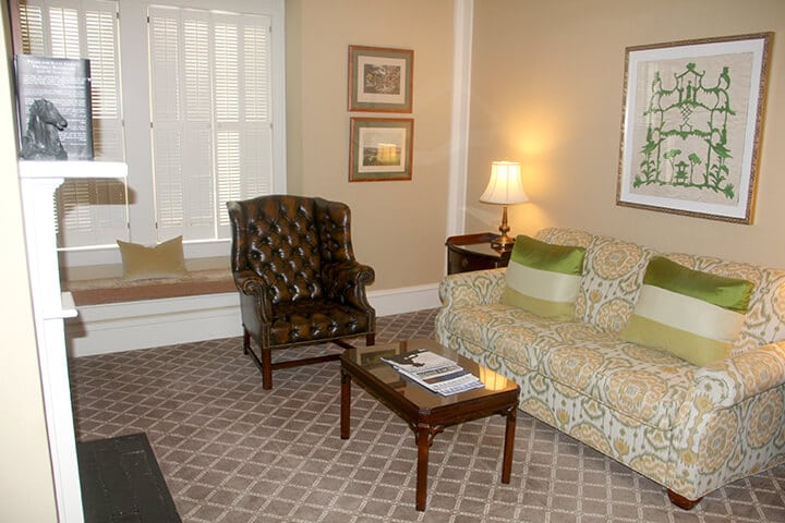 Sitting room with a green patterned sofa and brown chair in the suite at The Willcox Hotel.