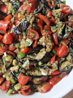 A closeup of eggplant salad in a white bowl.