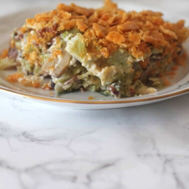 A closeup of a serving of Southern Broccoli Casserole on a plate over a marble board.