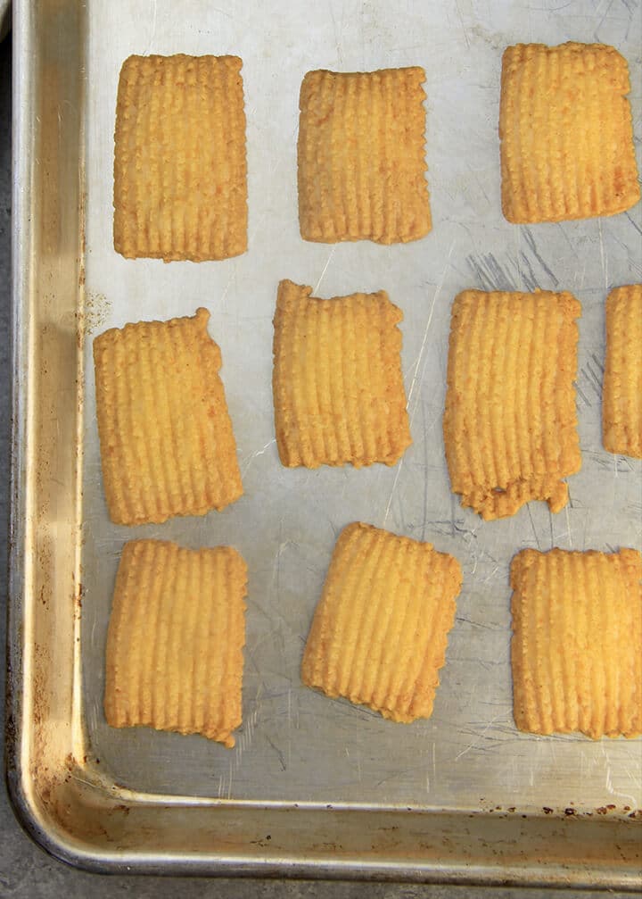 A sheet pan with baked cheese straws lined up.