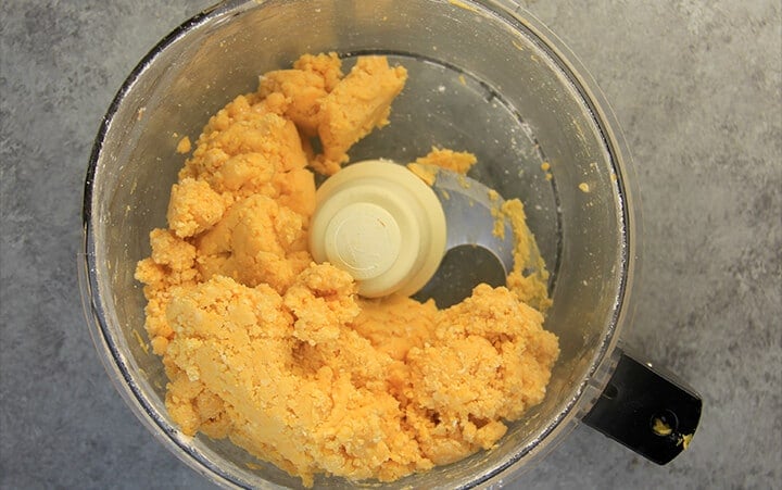 Cheese straw dough in the bowl of a food processor.