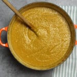 Butternut Squash Soup in a large pot on a grey board with a striped towel.