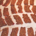 Pieces of caramelized bacon on a platter lined with parchment.