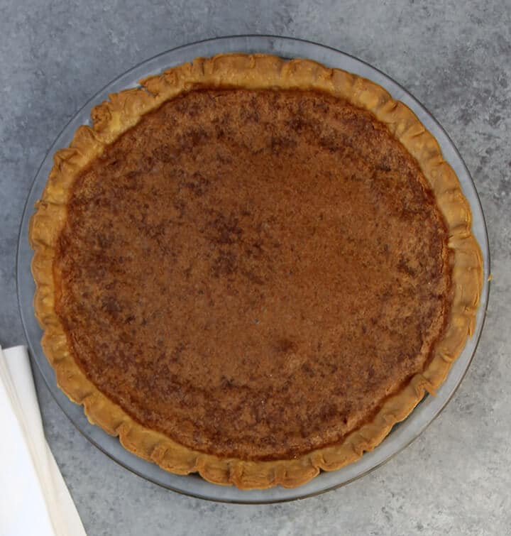 Overhead photo of a baked chess pie on a grey counter.