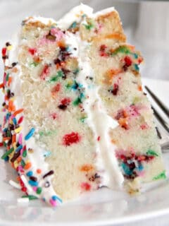A slice of funfetti cake on a plate with a fork.