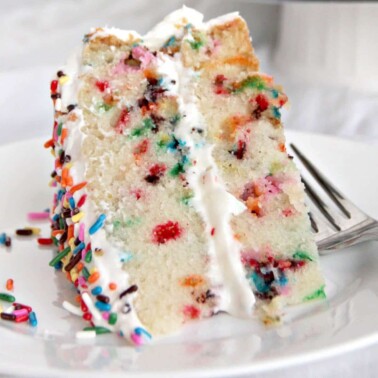 A slice of funfetti cake on a plate with a fork.