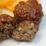 A white plate with three meatloaf muffins covered in ketchup sauce.