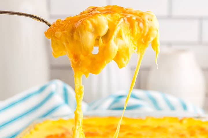 A spoonful of macaroni and cheese with cheese dripping down. 