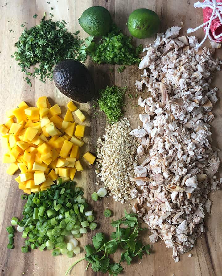 Chicken, cilantro, and other ingredients on a cutting board for chicken lettuce wraps.