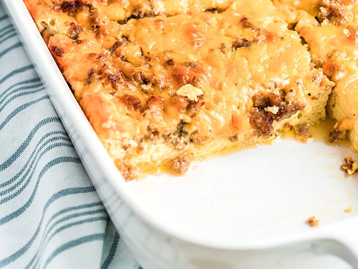 Overnight breakfast casserole in a white dish with a blue and white striped towel.