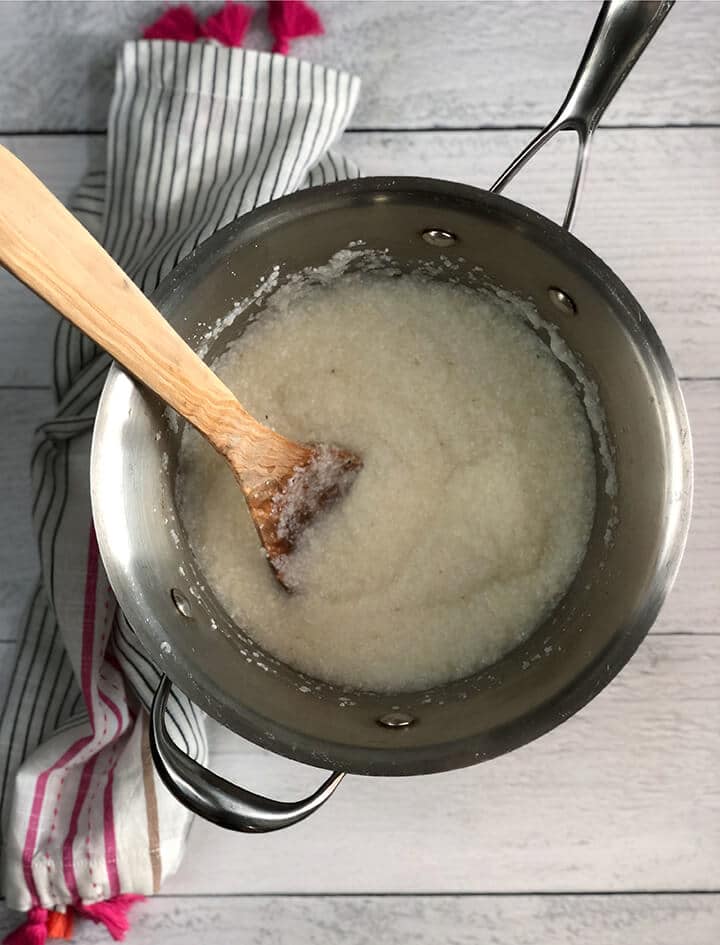A pot of grits and a wooden spoon.