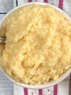 Closeup of cheese grits in white bowl with a spoon.