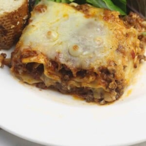 A closeup serving of lasagna without ricotta on a white plate.