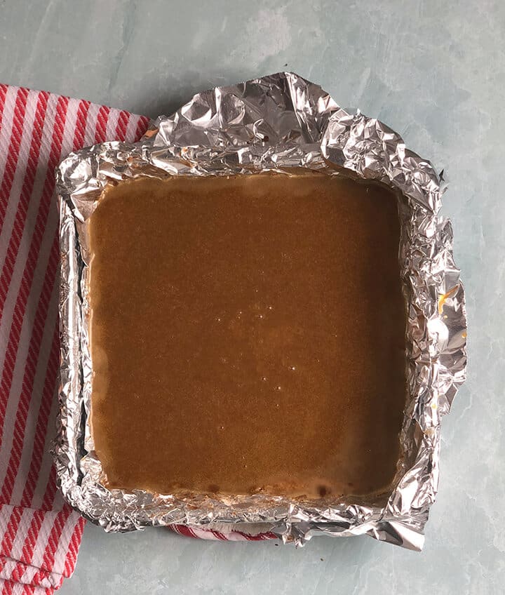 pecan pie filling in a square foil lined baking dish.