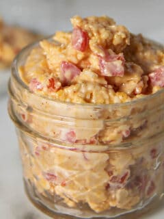 A serving of pimento cheese in a glass jar.