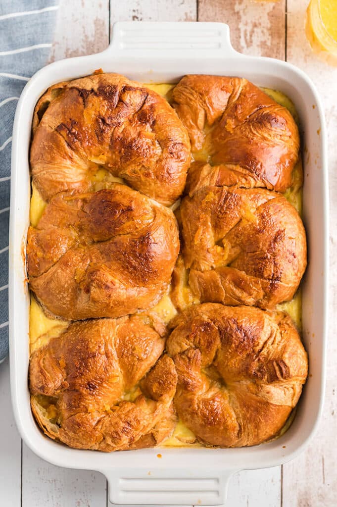 Croissant breakfast casserole baked in a white dish.