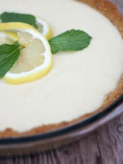 Side view of a whole lemon icebox pie on a wood background.
