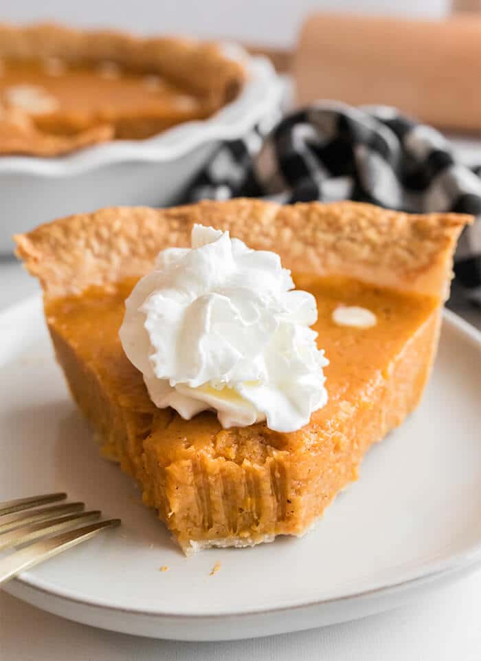 A slice of Southern sweet potato pie with a bite taken out and a fork on the white plate.