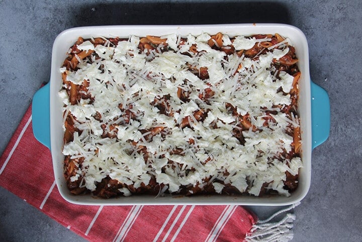 A blue baking dish filled with pasta and topped with cheese.