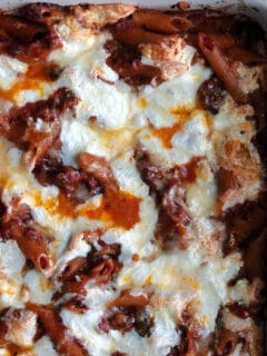 A closeup of baked pasta with sun-dried tomatoes and sausage.