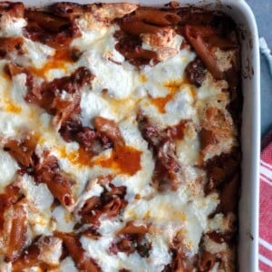 A closeup of baked pasta with sun-dried tomatoes and sausage.