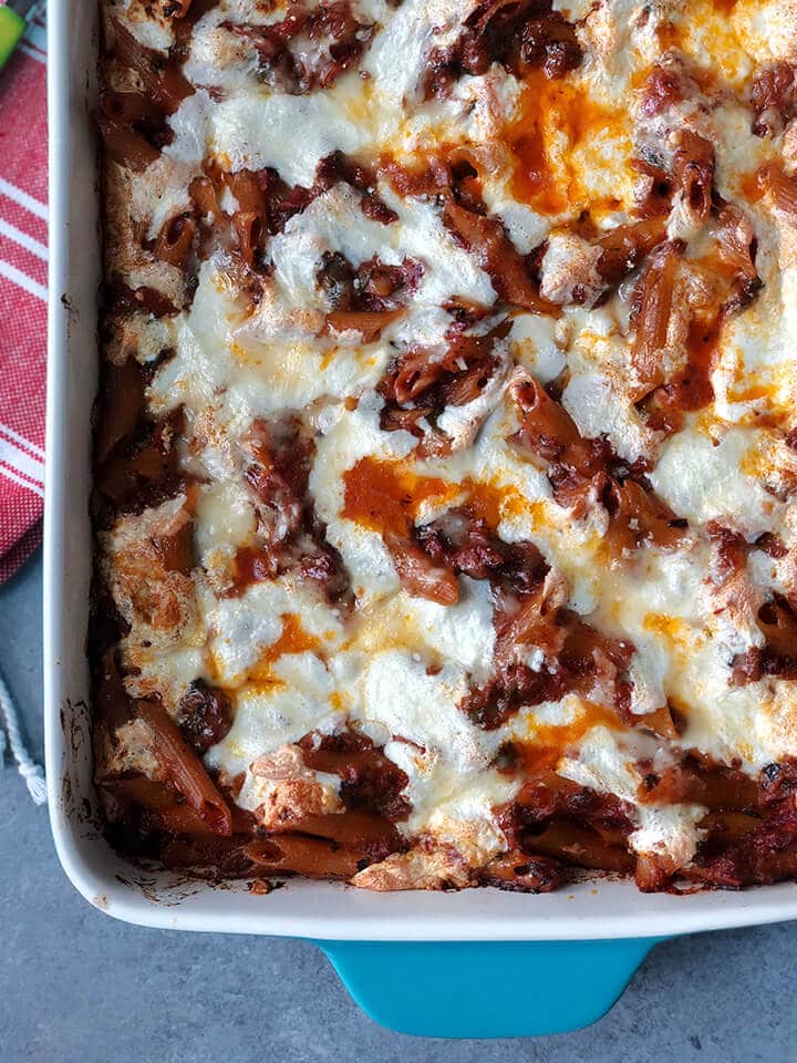 A closeup of a dish of baked pasta with penne and chicken.