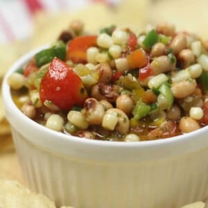 A white bowl filled with texas caviar and surrounded by chips.