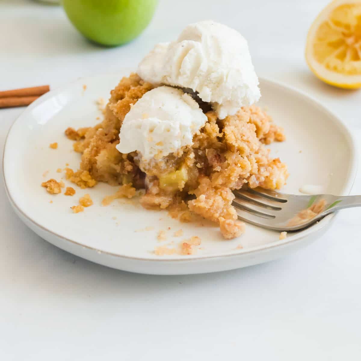 A serving of apple crisp on a white plate with vanilla ice cream. A favorite on the top ten list.
