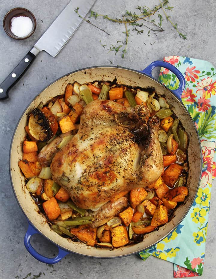 Overhead view of roasted chicken and vegetables in a blue braiser.