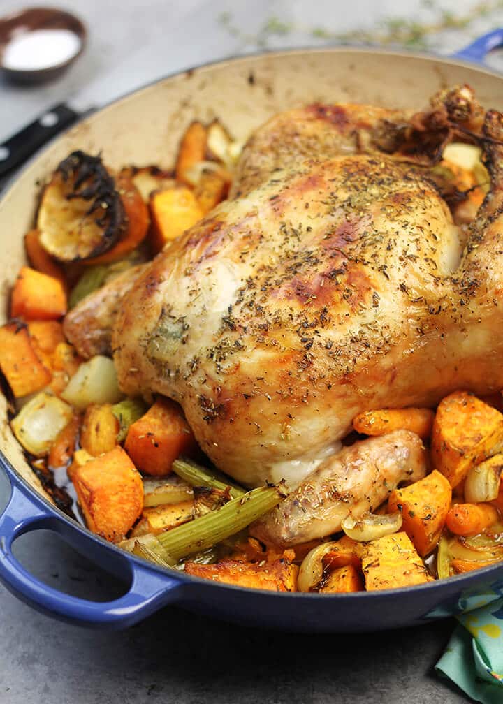 Side view of a pan of roasted chicken and vegetables.