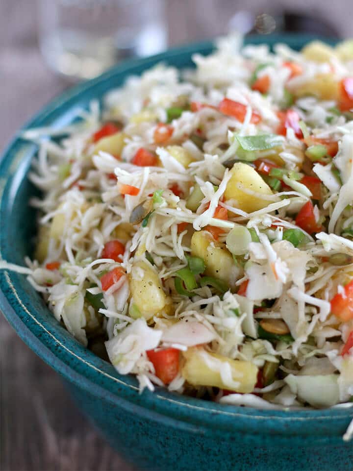 A blue bowl filled with pineapple coleslaw.