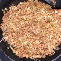 A wok with Filipino fried rice and a wooden spoon.
