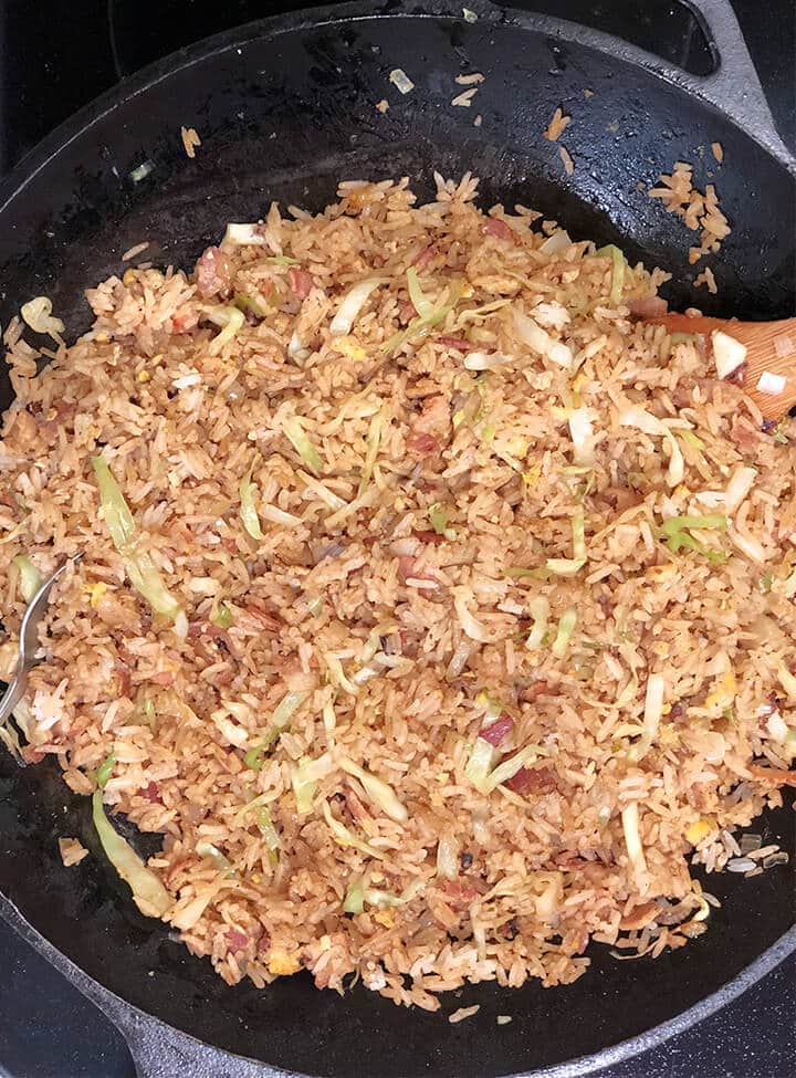 A wok with Filipino fried rice and a wooden spoon.