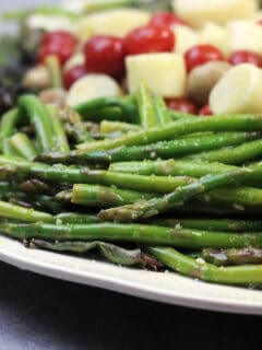 A white platter with marinated vegetables.