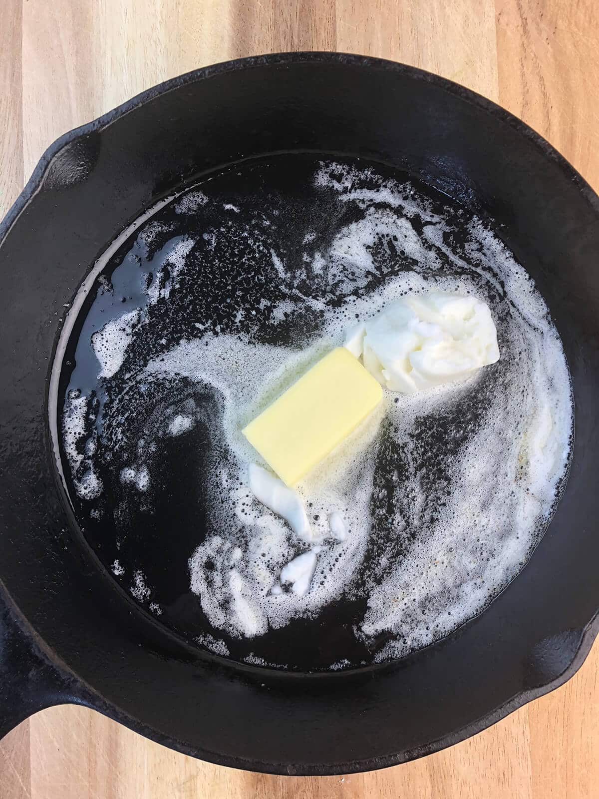 Butter and shortening melting in a cast iron skillet.