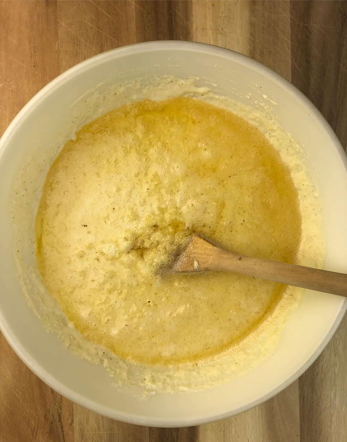 A bowl of cornbread batter with bacon grease being stirred in.