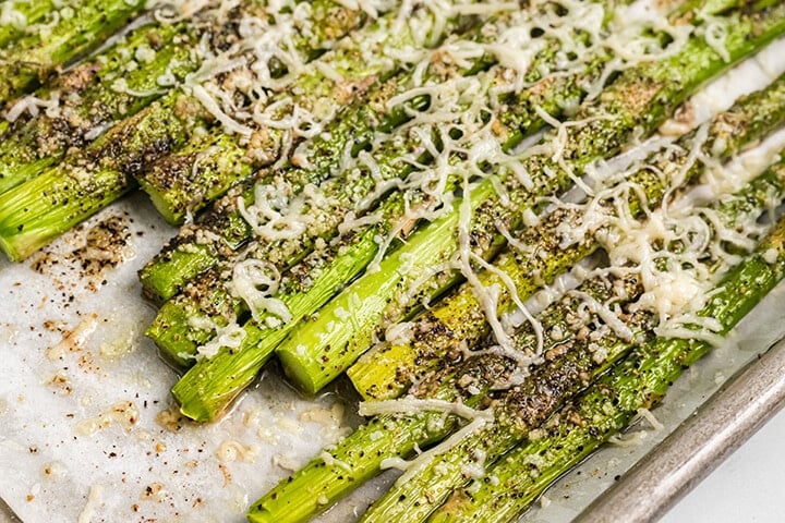 Roasted asparagus parmesan on a parchment paper lined baking sheet.