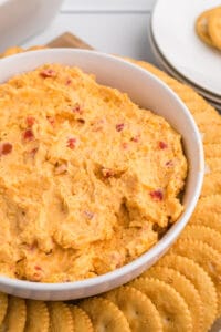 Closeup of a white bowl filled with pimento cheese surrounded by ritz crackers.