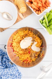 Grated cheese and pimentos in a stainless steel mixing bowl.