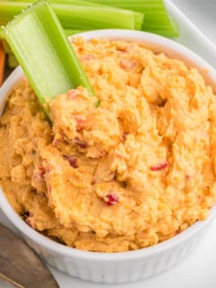 Pimento cheese in a small white bowl with celery.