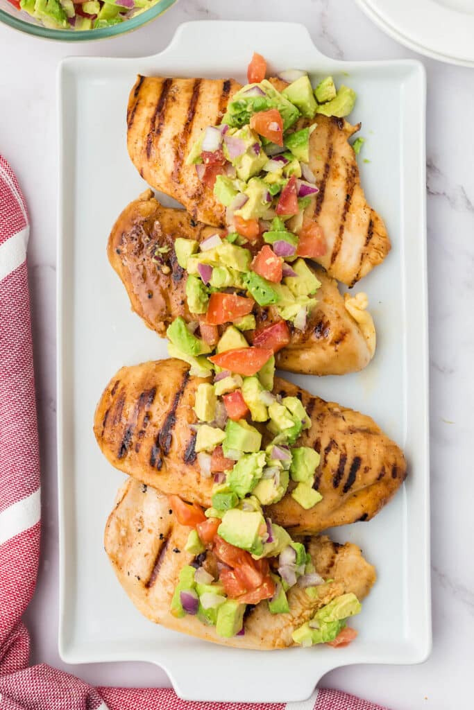 platter with four pieces of chicken topped with avocado salsa