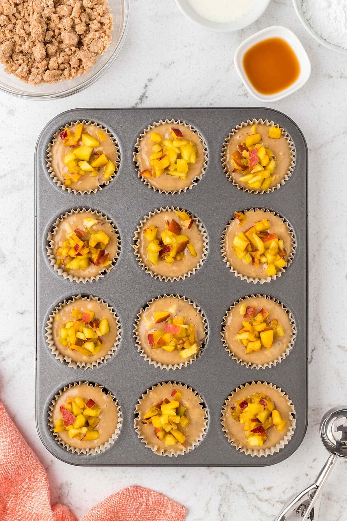 adding the peach muffin batter to the muffin tin
